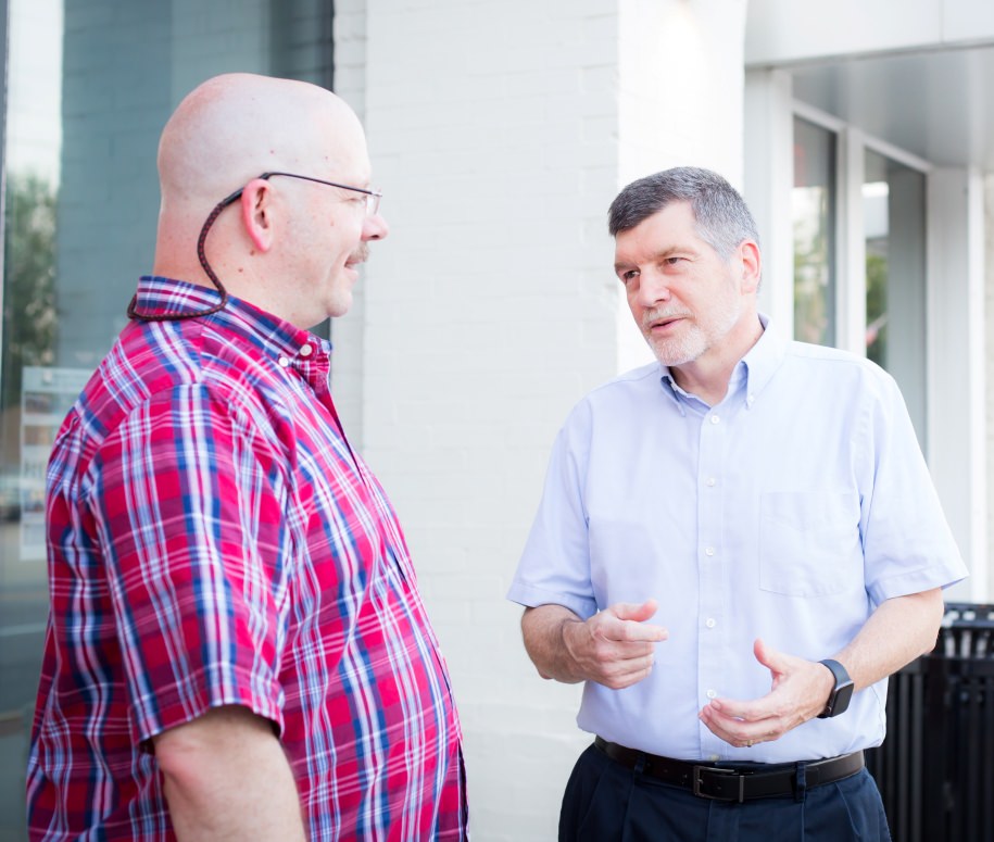 Raleigh IT consultants standing outside an office building discussing ways to help their clients better learn to use their technology.